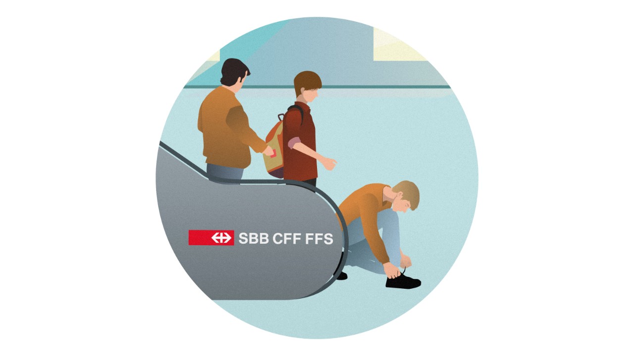 Ein Mann kniet sich am unteren Ende einer Rolltreppe nieder, um die Schnürsenkel zu binden. Der hinter ihm gehende Passant muss stehenbleiben. Hinter dem Passant fischt ein Komplize die Wertgegenstände aus dem Rucksack des Passanten.