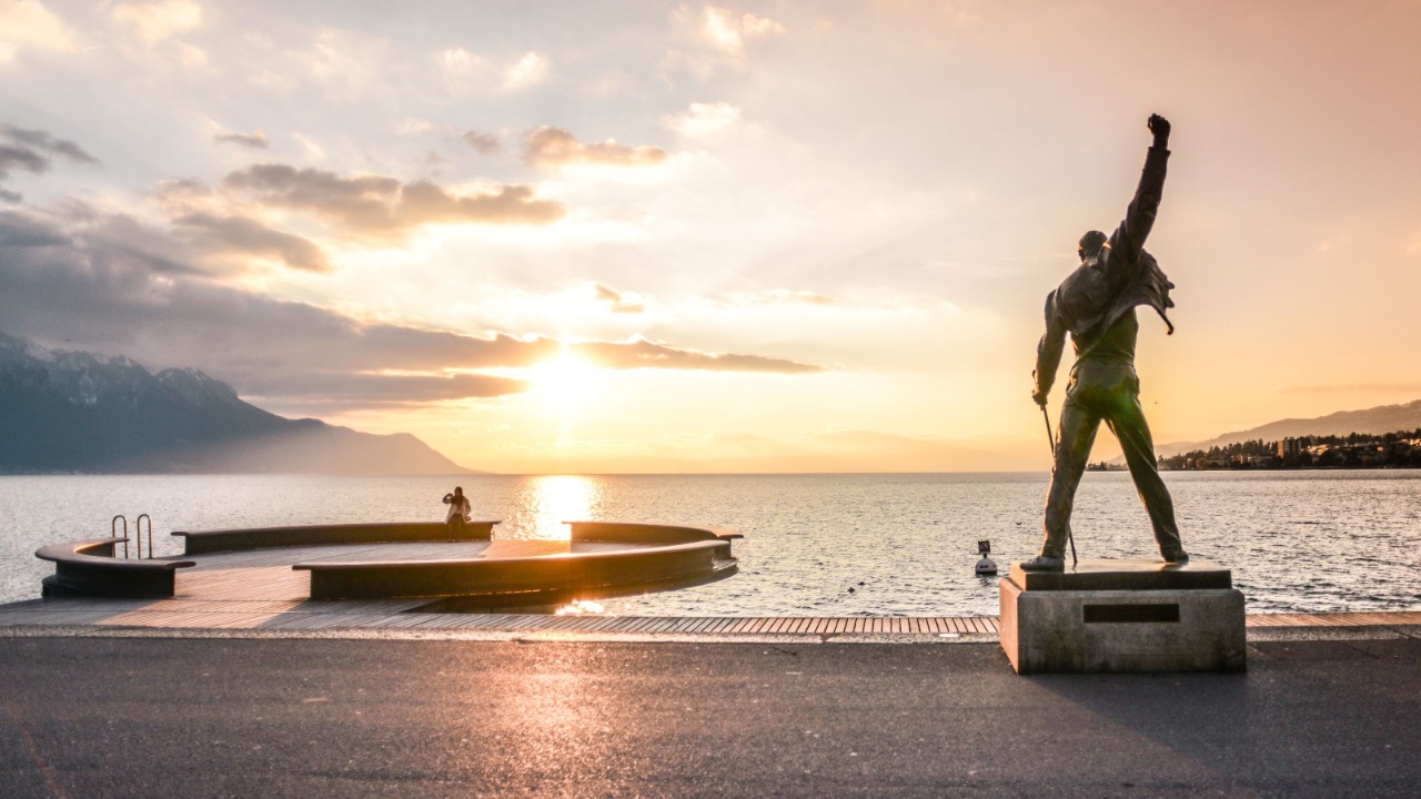 Rückansicht der Freddie-Mercury-Statue am See während eines Sonnenuntergangs.