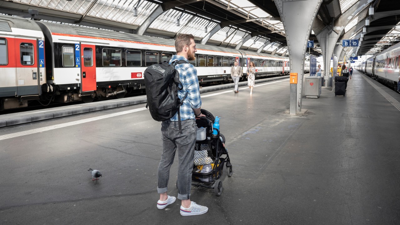 Stellen Sie den Kinderwagen parallel zum Gleis und arretieren Sie die Bremsen.